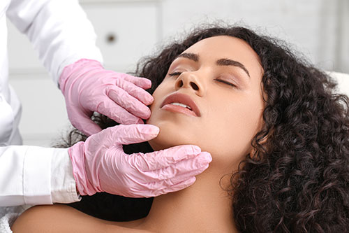 Gloved hands checking facial treatment
