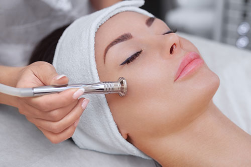 he cosmetologist makes the procedure Microdermabrasion of the facial skin of a beautiful, young woman in a beauty salon.